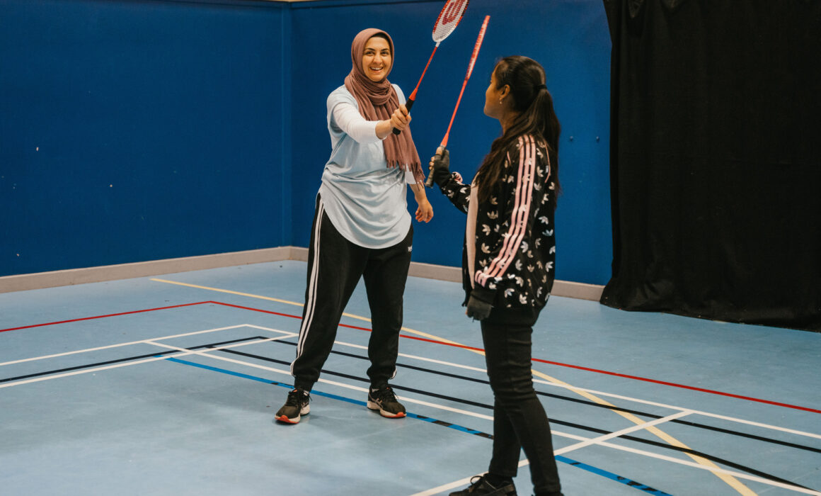 Two asian women smiling as they play badminton