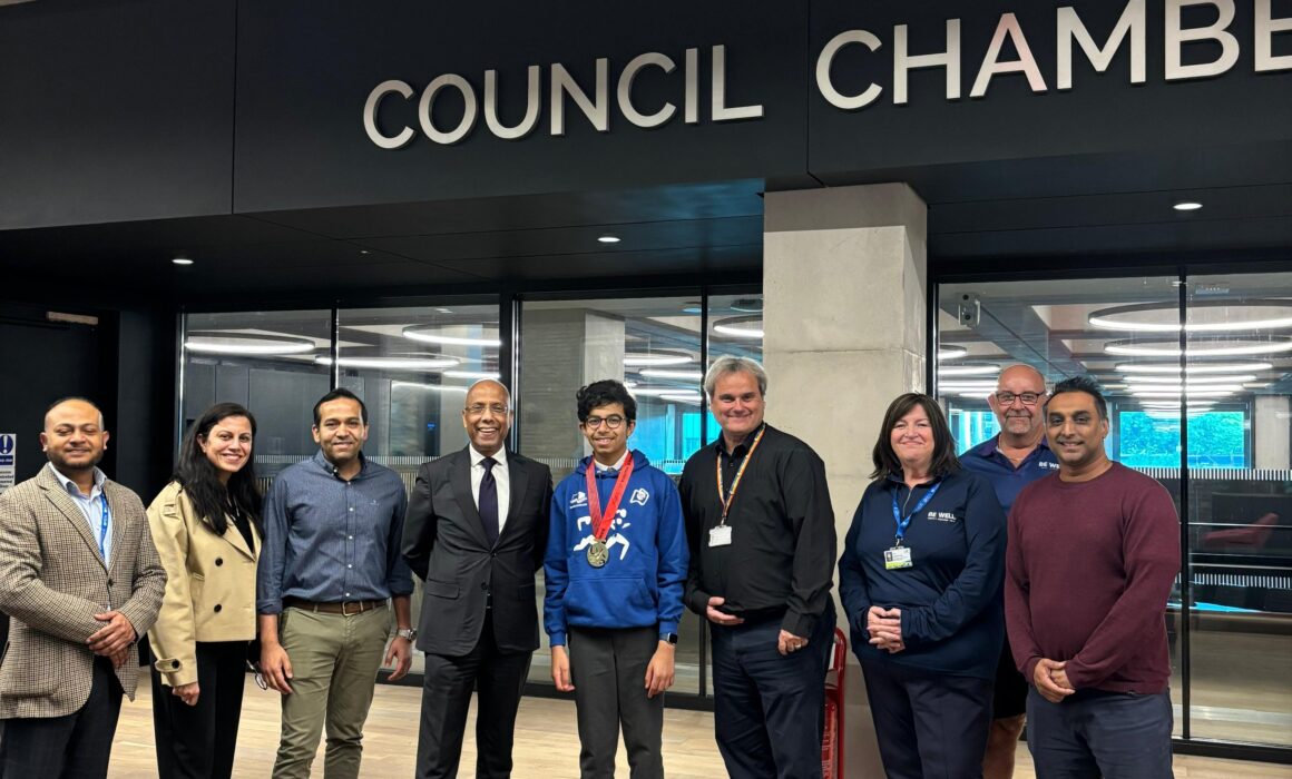 Photo of Samarth swimming gold medalist being presented his medal by the Mayor alongside Be Well Swimming staff and council lead members