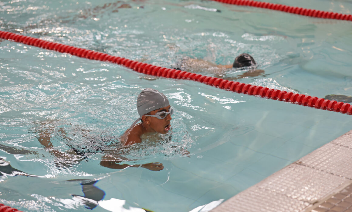 A young boy swimming in a siwmming pool lane